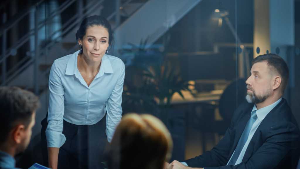 Corporate Meeting Room: Confident Female Executive Director Decisively Leans on the Conference Table and Delivers Report to a Board of Executives about Company’s Record Breaking Revenue