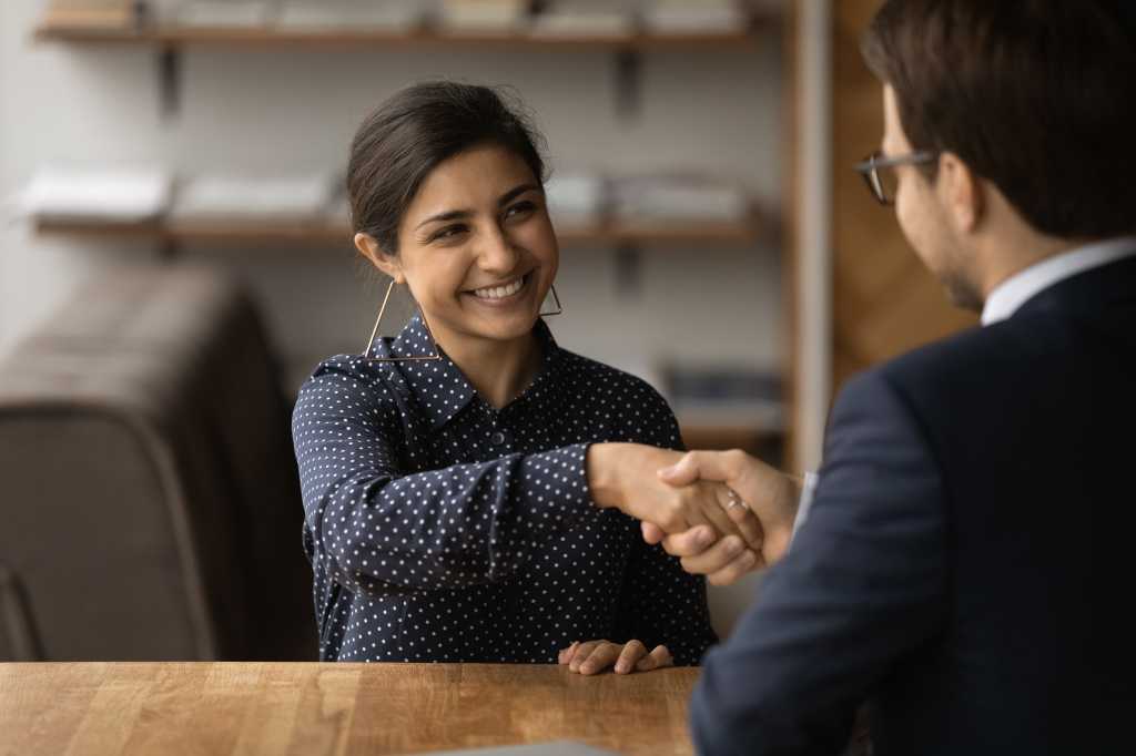 Greetings, you are hired. Happy young indian female successful job seeker shake hand of male hr manager. Diverse business partners handshake close deal come to agreement