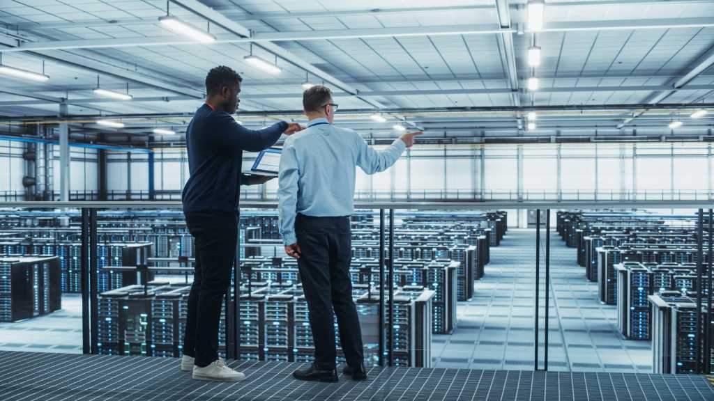 Two male colleagues in data center looking at servers