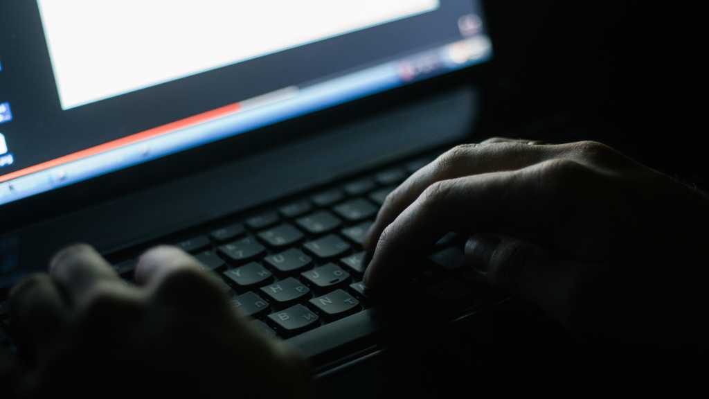 hands typing on laptop in dark room