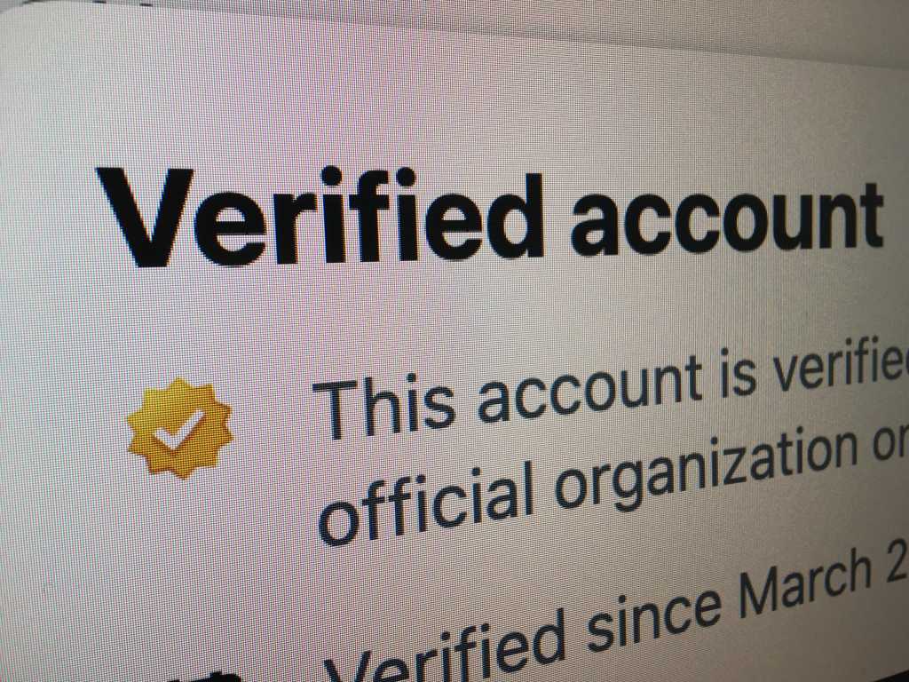 A gold checkmark on an X (formerly Twitter) verified account.